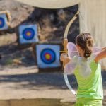 A camper aiming an arrow at a target