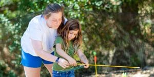 Staff helping camper with archery