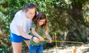 Staff helping camper with archery