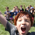 A group photo of campers with a boy jumping 